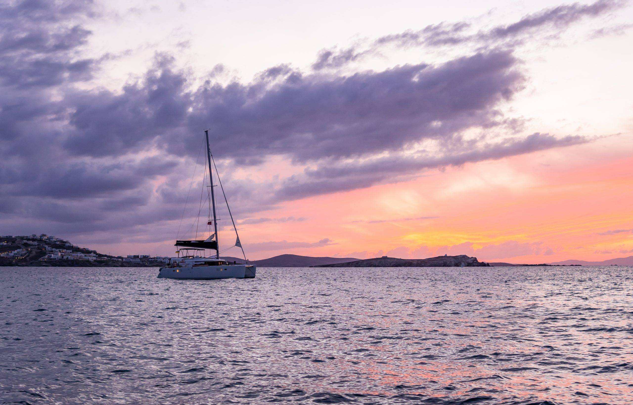 7 Minimalist Ways to Deal With Uncertainty in Your Life - featured -sailing catamaran at sunset in Mykonos, Greece