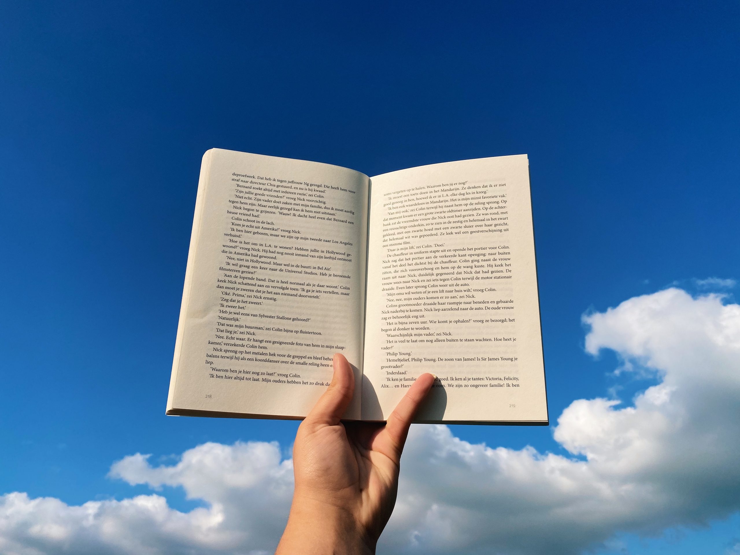 5 Life-Changing Books to Read in 2021 - hand holding a book in the clouds