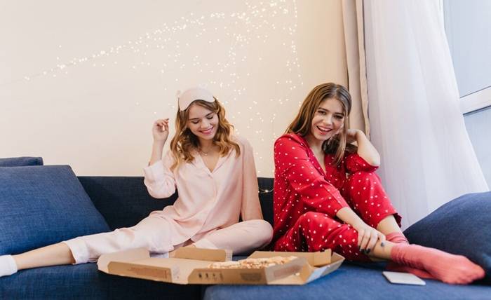 The Best Christmas Pyjamas for a Cosy Festive Season carefree girls cute night suits eating pizza together romantic young woman red pajama sitting sofa with sister enjoying fast food 197531 21434